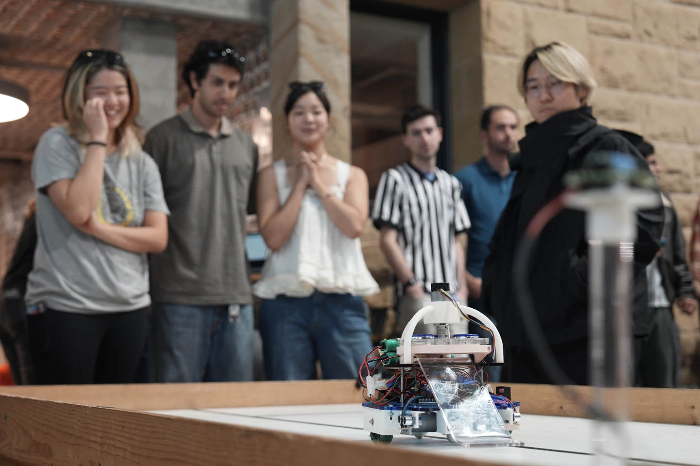 Turty Droid on the curling table, with the team watching the competition.
